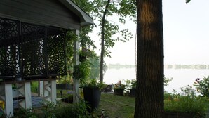 A house with a porch, potted plants, and a view of a lake.