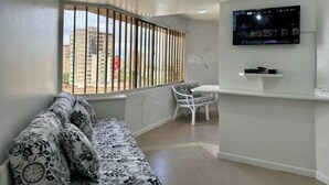 Una sala de estar con un sofá, una mesa de comedor y un televisor instalado en la pared.