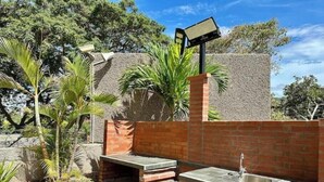 Un área de cocina exterior con pared de ladrillo, pileta y parrilla integrada.