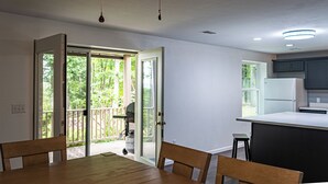 Eine moderne Küche mit einer großen Kochinsel, einem Essbereich inklusive Tisch und Stühlen sowie einer Glastür zum Balkon.