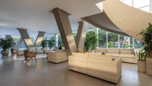 A spacious lobby with modern furniture, large windows, and a unique architectural design featuring prominent concrete pillars. - Luxury Loft Porto Horizonte Beach meters away (Magdalena)