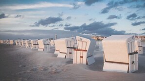 Rows of white, boxy, portable structures with numbers on them, likely indicating room numbers, on a sandy surface. - Koralle (Rostock)