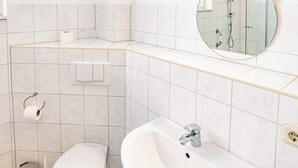A modern bathroom with a toilet, sink, and shower. - Seestern (Rostock)