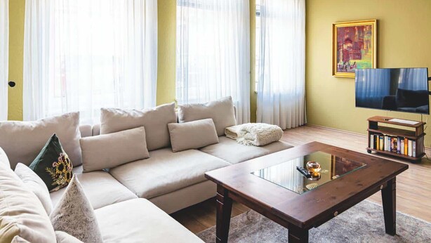 A living room with a sofa, a glass coffee table, and a television. - Seestern (Rostock)