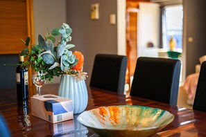 A dining table with a vase of flowers, a wine bottle, and a box.