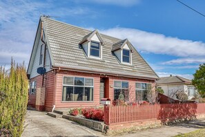 A two-story house with a gabled roof, a red picket fence, and a mailbox.