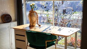 A room with a wooden table, a green chair, and a vase with flowers on the window sill. - StayAU Private Two-Storey 6 Beds House Wendouree (Wendouree)