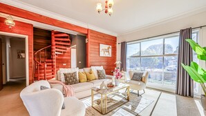 A living room with a red accent wall, a staircase, a large window with a view, and a cozy seating area. - StayAU Private Two-Storey 6 Beds House Wendouree (Wendouree)