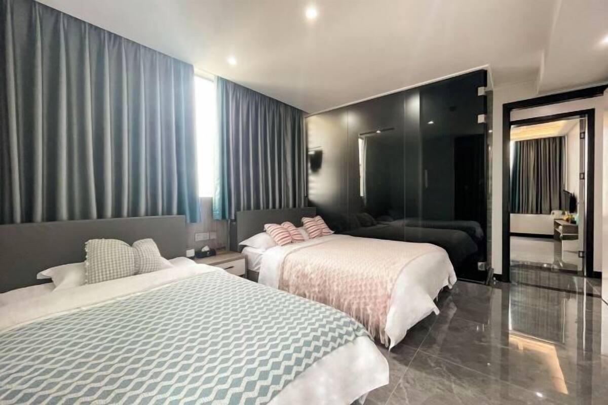 Ein modernes Hotelzimmer mit zwei Betten, einem großen Spiegel und einem Badezimmer mit Dusche und Toilette.