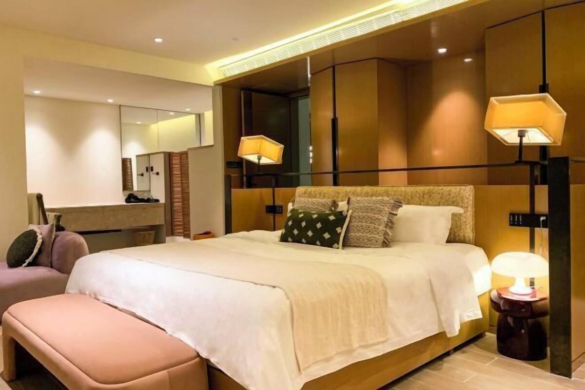 Ein Hotelzimmer mit einem großen Bett, Nachttischlampen, einem Spiegel und einem kleinen Tisch.
