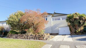 A single-story house with a garage, a stone wall, and a lawn.