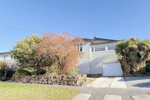 A single-story house with a garage, a stone wall, and a lawn. - StayAU 2BR Home w/ Stunning Views in Tasmania (Trevallyn)