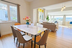 A spacious living room with a dining area, large windows, and a view of the outdoors. - StayAU 2BR Home w/ Stunning Views in Tasmania (Trevallyn)