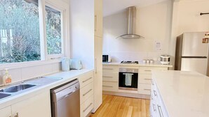A modern kitchen with a dishwasher, oven, and a window with a view of trees.