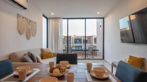 Una sala de estar moderna con comedor, ventanas grandes y vistas a la ciudad.