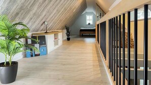 A spacious loft bedroom with a sloped ceiling, a large window, and a wooden floor. - Lüttjet Huus (Lügde)