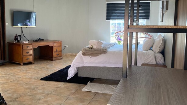 Un dormitorio con cama, escritorio, televisor y literas.