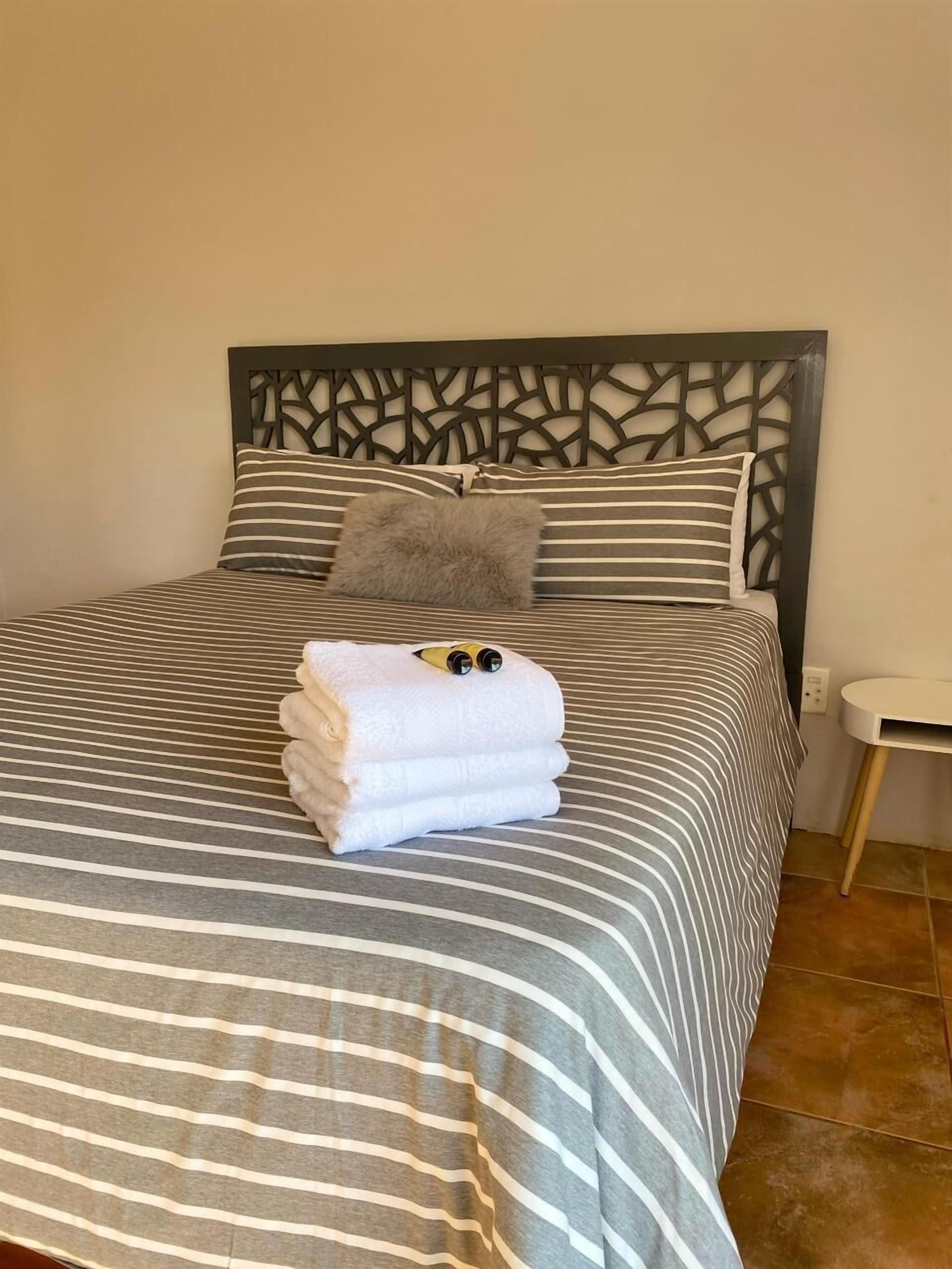 A neatly made bed with striped bedding and a decorative headboard.