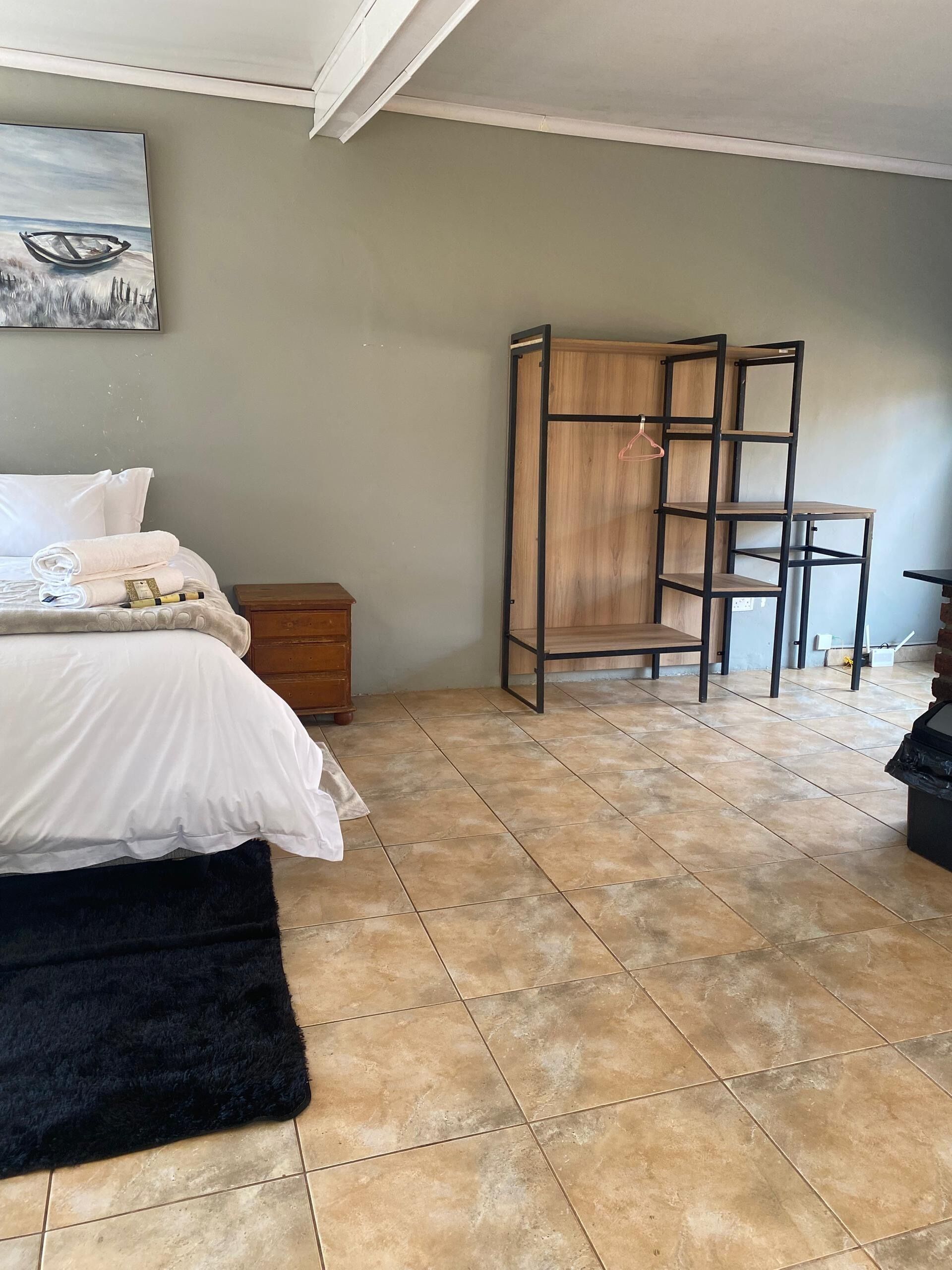 Quarto com cama, guarda-roupa de madeira, piso de azulejos e um quadro na parede.
