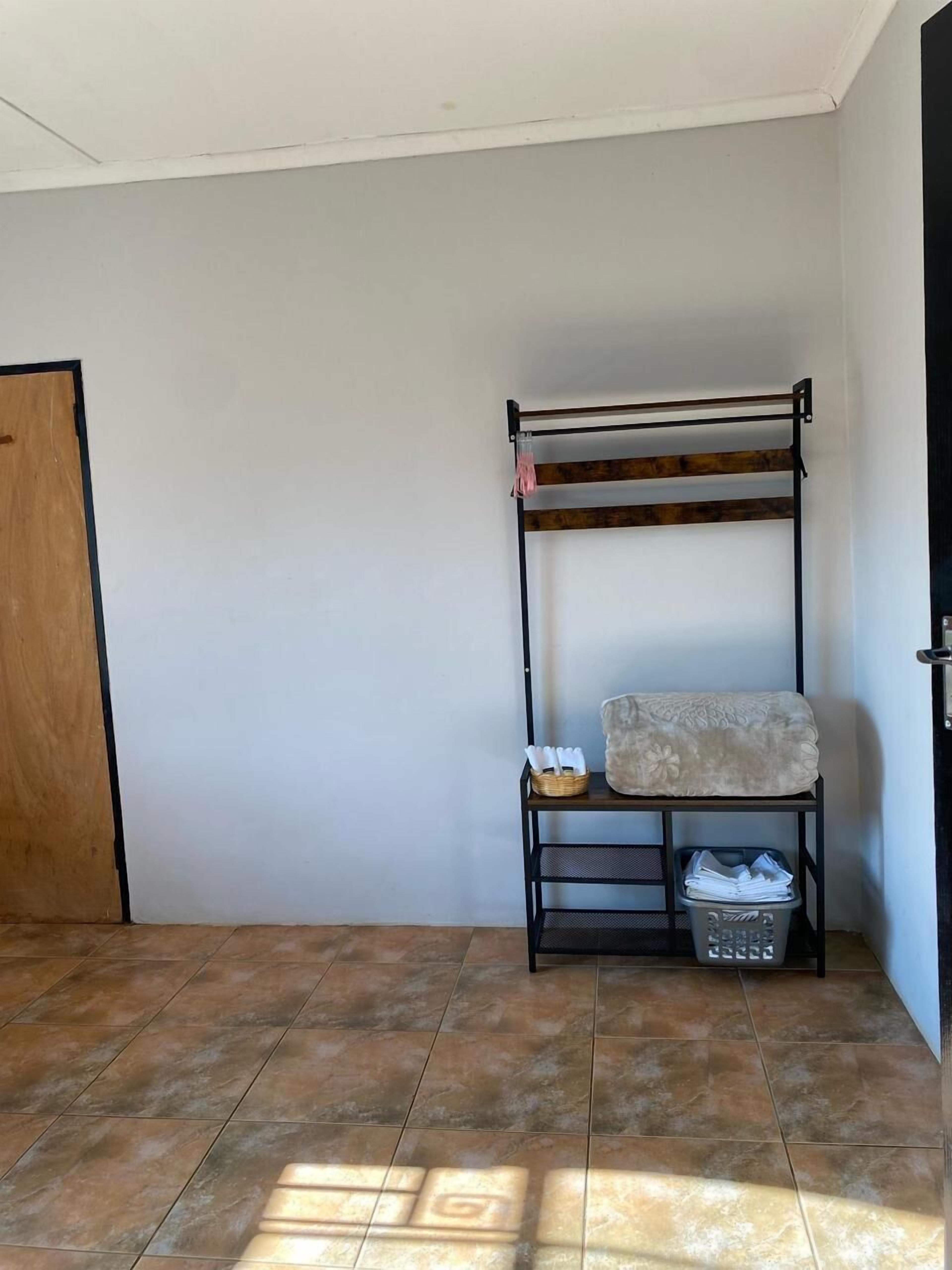 A small, tiled room with a metal bench and a basket containing toiletries.