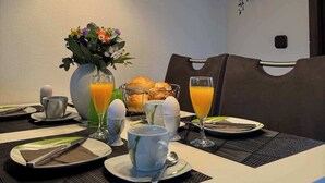 A modern dining area with a table set for breakfast, including croissants, eggs, and orange juice. - Sauerländer Henne-Lütt (Meschede)