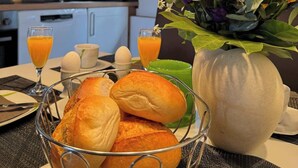 A breakfast setting with bread, a vase of flowers, and orange juice. - Sauerländer Henne-Lütt (Meschede)