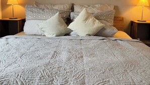 A neatly made bed with patterned pillows, two wall-mounted artworks depicting nature, and two bedside lamps. - Sauerländer Henne-Lütt (Meschede)