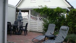 Een terras met twee gestreepte loungestoelen, een tafel en stoelen.