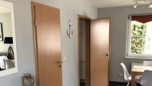 Een moderne kamer met een donkere vloer, witte meubels en een raam met uitzicht op groen.