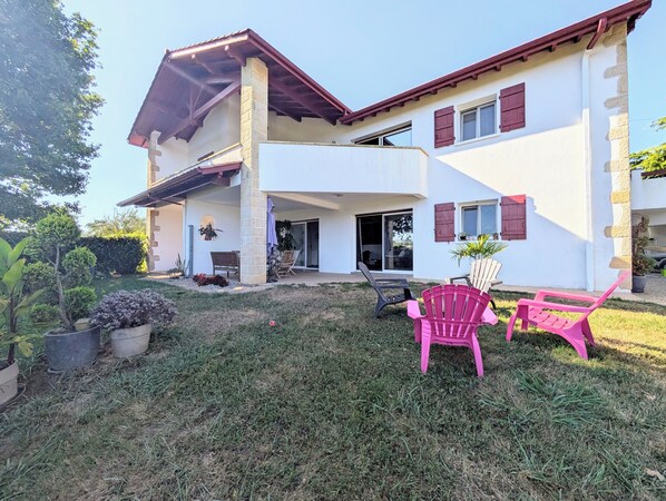 A two-story house with a covered patio, outdoor seating, and a well-maintained lawn.