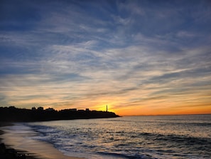 A coastal sunset with a lighthouse silhouette, calm sea, and distant buildings. - Hasparren, family apartment 114m², garden and view, sleeps 6. (Hasparren)