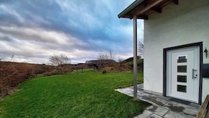 A house with a white exterior, a covered porch, and a door with a glass panel. - Apfelhaus am Hennesee (Meschede)