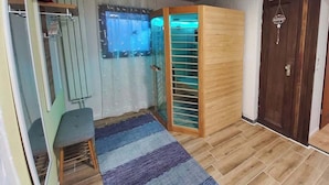 A room with a wooden floor, a blue striped rug, a wooden cabinet, a glass door, and a dark wooden door. - Apfelhaus am Hennesee (Meschede)