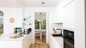 Una cocina moderna con armarios blancos, una isla de madera y vistas a un comedor.