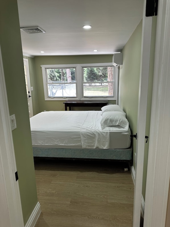 A bedroom with a bed, two windows, and a door.