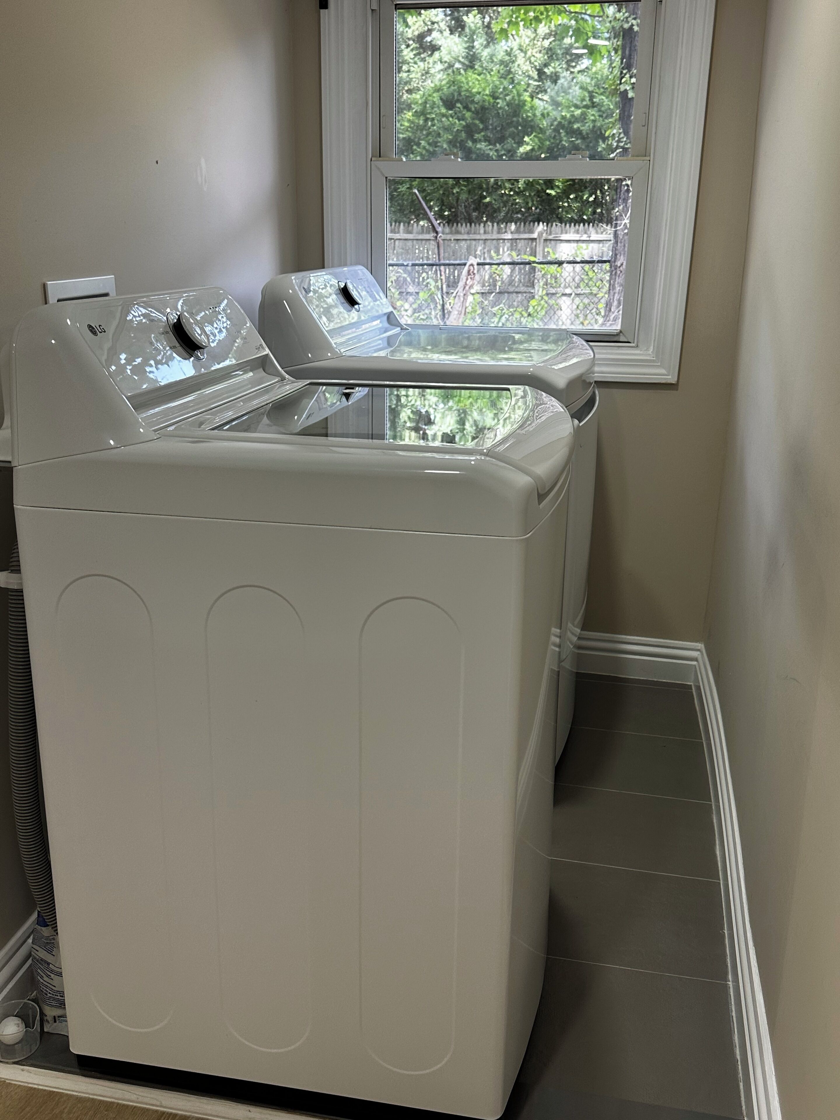 Een wit wasmachine en droger met voorlaadopening in een wasserij met een raam erboven.