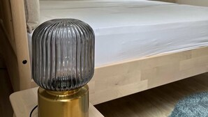 Ein Hotelzimmer mit einem Bett, einem an der Wand montierten Fernseher und einem Tisch mit einer Lampe.