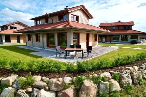 Una casa de dos pisos con un porche cubierto y un jardín.