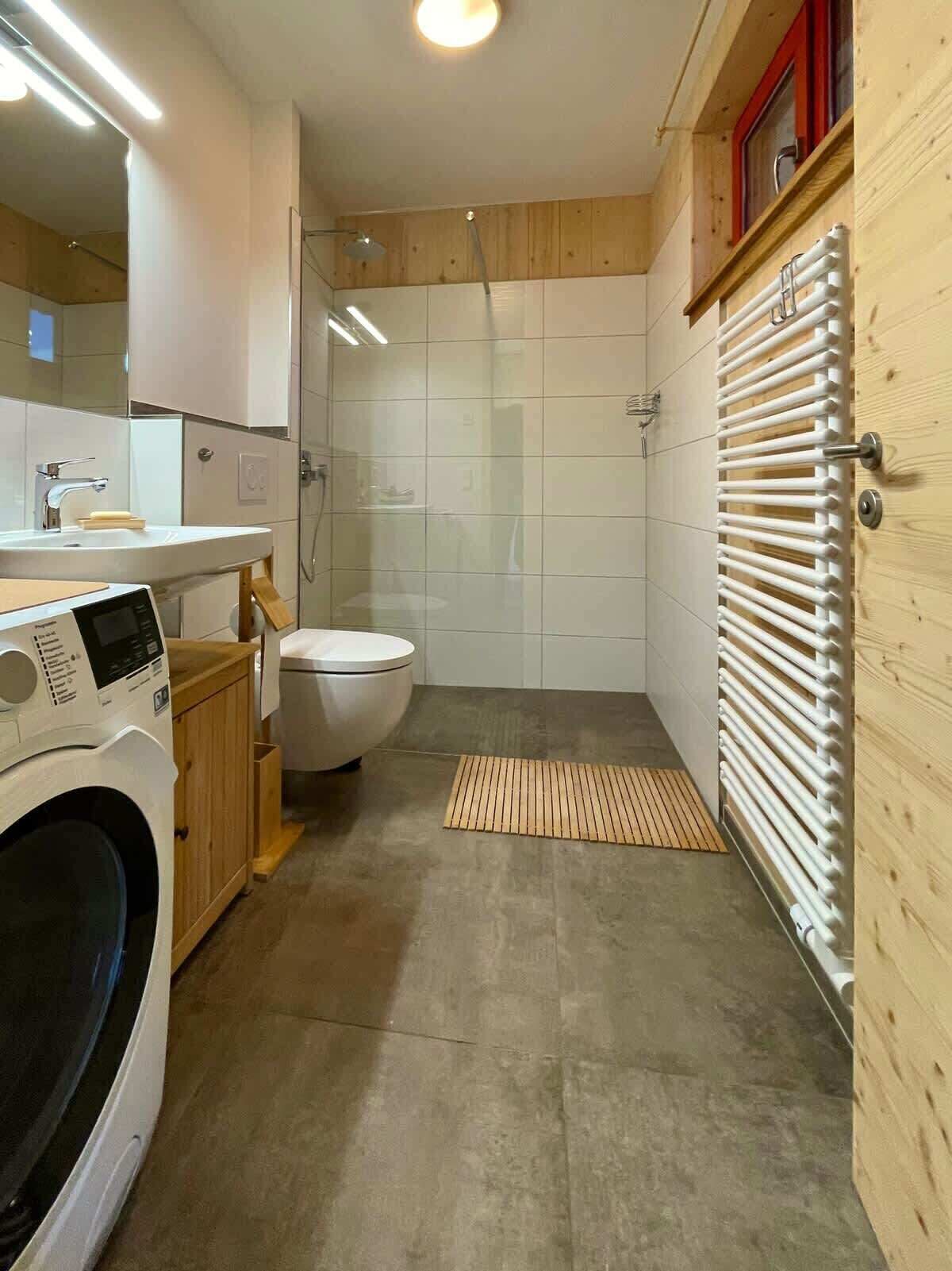 Ein kleines Badezimmer mit Waschmaschine, Toilette und Duschbereich.