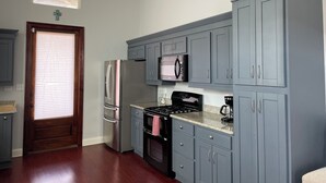 Una cocina con gabinetes grises, electrodomésticos de acero inoxidable y una puerta de madera.