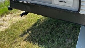 Een camperkeuken met houten kastjes, een zwarte koelkast en een spoelbak.