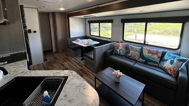 Een compact RV-interieur met een kitchenette, een eethoek en een zithoek met uitzicht.
