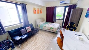 Ein gemütlicher Raum mit Bett, Sofa, Esstisch und kleinem Schreibtisch.