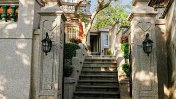 Una escalera de piedra que lleva a la entrada de un edificio con detalles decorativos y un farolillo a cada lado.