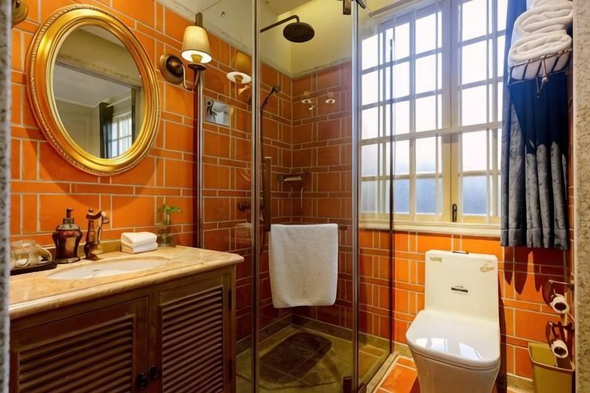 A bathroom with a glass-enclosed shower, a white toilet, and a large mirror.