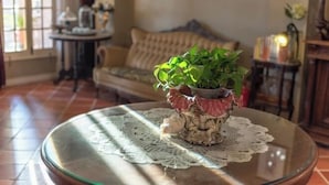 A round glass table with a lace tablecloth, a potted plant, and a small table lamp. - Lilac Garden Hotel (Xiamen)