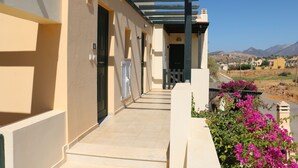 A building with a covered walkway, a door, and a view of a landscape with mountains. - Seaview Tranquility Steps to Ocean's Edge, Sunsets (Rethimno)