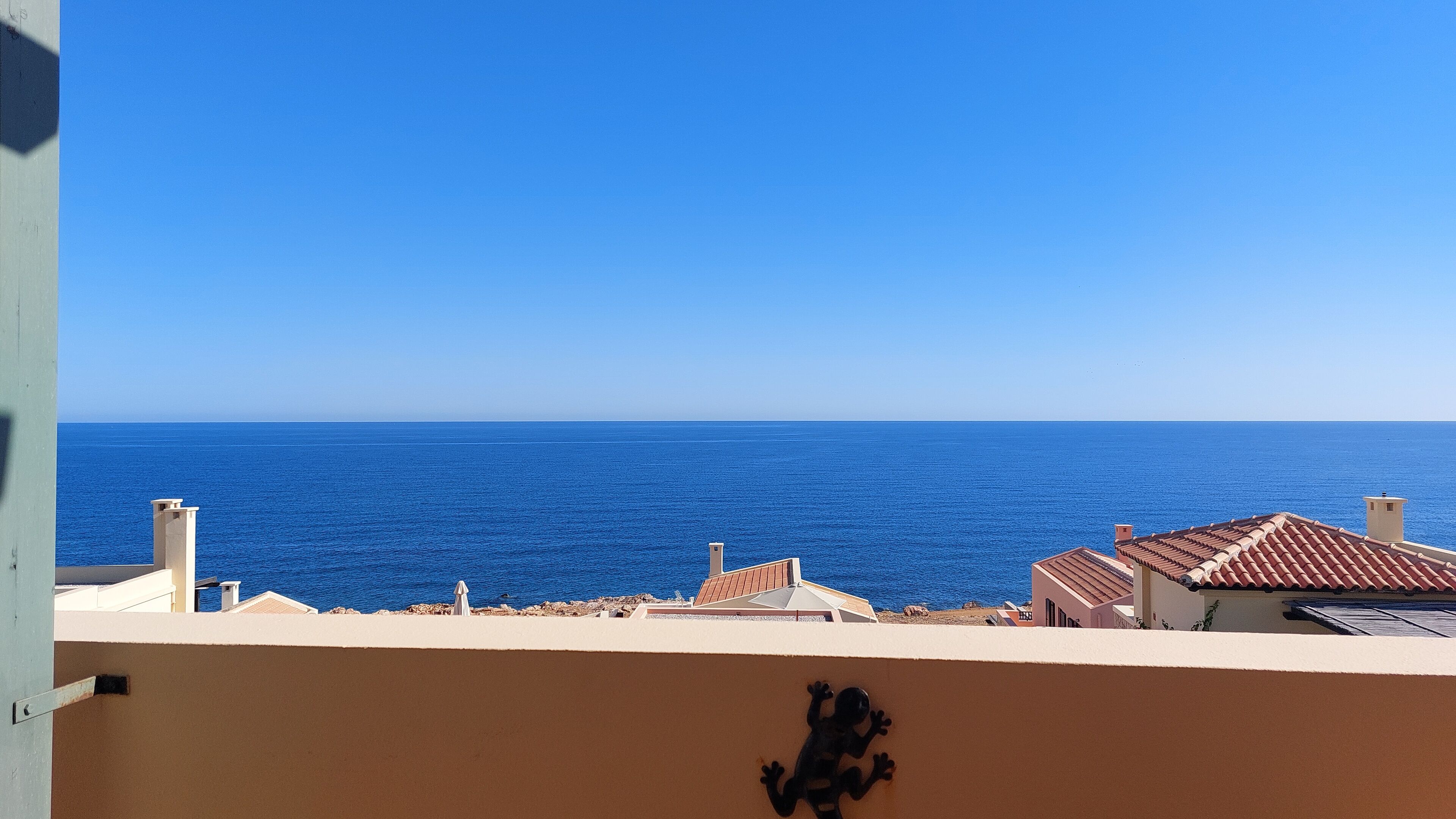 Vistes costaneres amb cel serè, un edifici amb teulada de terracota i un mar tranquil.