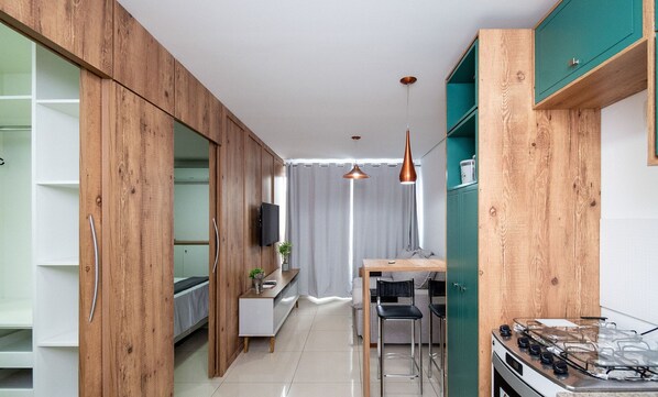 A modern kitchen with wooden cabinets, a dining area with a table and chairs, and a visible stove. - DNA Smart Style - DNA (Goiânia)