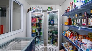 Una pequeña tienda de conveniencia con dispensadores de bebidas refrigeradas, estantes llenos de bocadillos y una variedad de productos envasados.